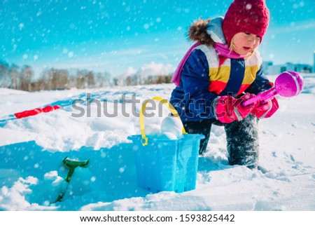 little girl making snowball in winter nature