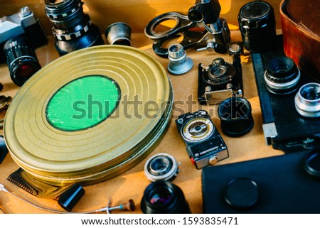 Retro photographic mockup. Metal round box from film from left side and vintage photographic accessories and quipments around on Wooden Background.