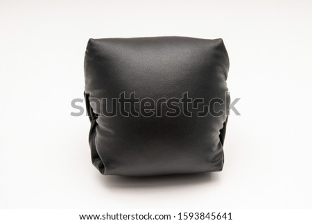 Black leather pillow on a light background. Space for text, copy space.