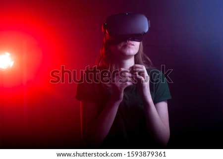 young girl in virtual reality glasses at night in the game room, a woman surprised in virtual space