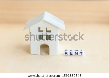 Miniature toy model house with inscription RENT letters word on wooden backdrop. Eco Village abstract environmental background. Real estate mortgage property insurance sweet home ecology rent concept