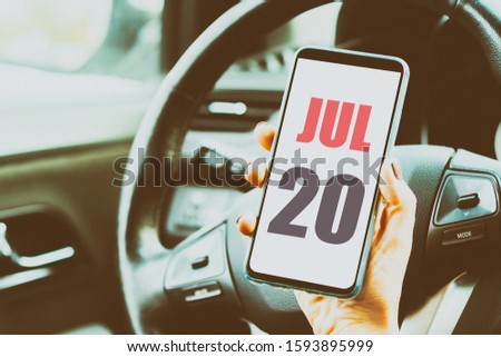july 20th. Day 20 of month,Calendar date. Month and day placed on a smartphone screen in womans hand in car interior. artistic coloring.  summer month, day of the year concept