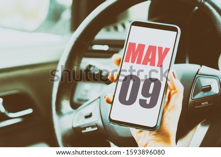 may 9th. Day 9 of month,Calendar date. Month and day placed on a smartphone screen in womans hand in car interior. artistic coloring.  spring month, day of the year concept