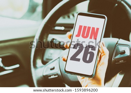 june 26th. Day 26 of month,Calendar date. Month and day placed on a smartphone screen in womans hand in car interior. artistic coloring.  summer month, day of the year concept