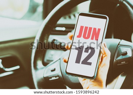 june 12th. Day 12 of month,Calendar date. Month and day placed on a smartphone screen in womans hand in car interior. artistic coloring.  summer month, day of the year concept
