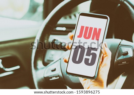 june 5th. Day 5 of month,Calendar date. Month and day placed on a smartphone screen in womans hand in car interior. artistic coloring.  summer month, day of the year concept