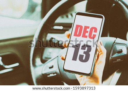december 13th. Day 13 of month,Calendar date. Month and day placed on a smartphone screen in womans hand in car interior. artistic coloring.  winter month, day of the year concept