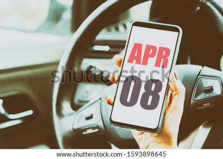 april 8th. Day 8 of month,Calendar date. Month and day placed on a smartphone screen in womans hand in car interior. artistic coloring.  spring month, day of the year concept