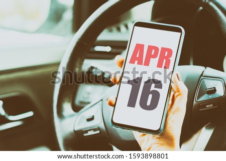 april 16th. Day 16 of month,Calendar date. Month and day placed on a smartphone screen in womans hand in car interior. artistic coloring.  spring month, day of the year concept