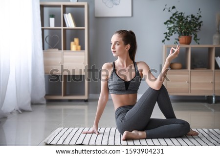 Beautiful young woman practicing yoga at home Royalty-Free Stock Photo #1593904231