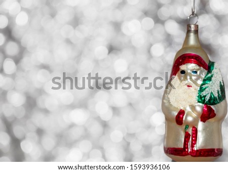Vintage decorative christmas bauble in a shape of the saint Nicolas or Ded Moroz with a silver bokeh blury star background.