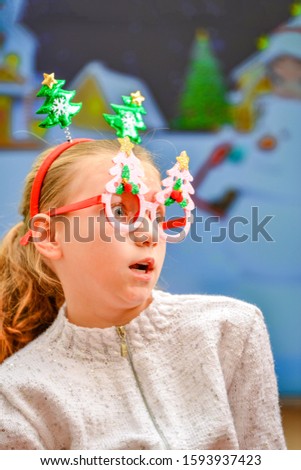 A surprised girl at Christmas and New Year in a festive tinsel looks away with delight and an open mouth.
