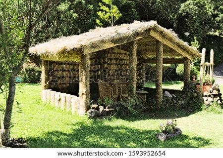 Wooden hut with wooden chairs under the straw roof in the countryside (Madeira, Portugal, Europe)