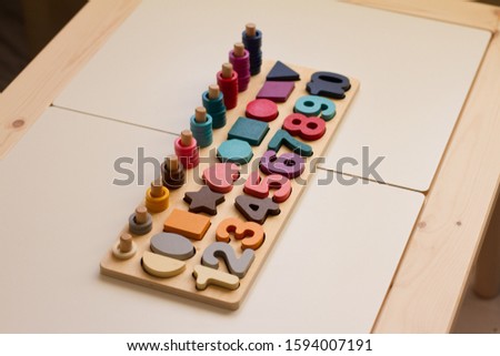 Toy made of wood on the study of numbers, shapes and colors. A useful game for a child on a white wooden table. Montessori Education. Materials for the school. Materials on geometry and mathematics.