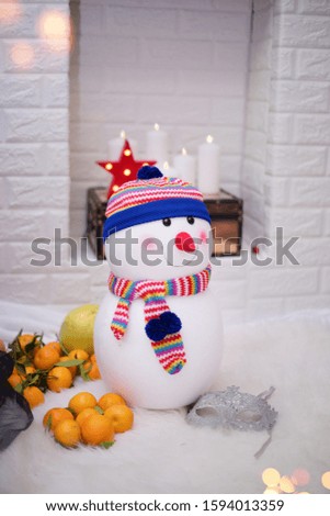 cool snowman toy in the cozy livingroom with mandarines beside a