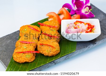 Picture of Thai food called fish cakes mixed with Thai spices and sweet sauces, a traditional Thai food that is popular all over the world on a beautiful tray.