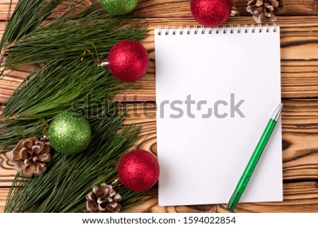 Christmas background with blank notebook, pine branches and Christmas toys on wooden table. Top view. Copy space. Flat lay
