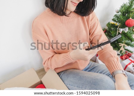 young asian woman sit on floor, using mobile phone, and holding credit card for christmas online shopping