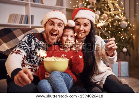 Happy family indoors in christmas hats have fun together and celebrating new year.