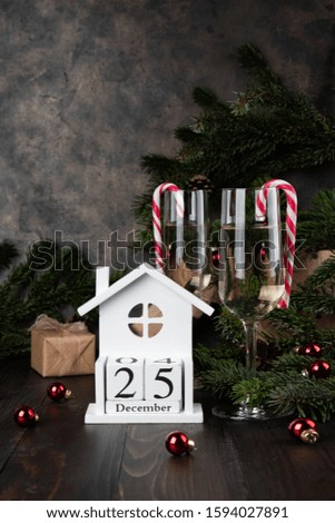 Christmas glasses of champagne and fir tree branches on old wooden background, dark image in rustic style, selective focus. 25 december on the cube calendar