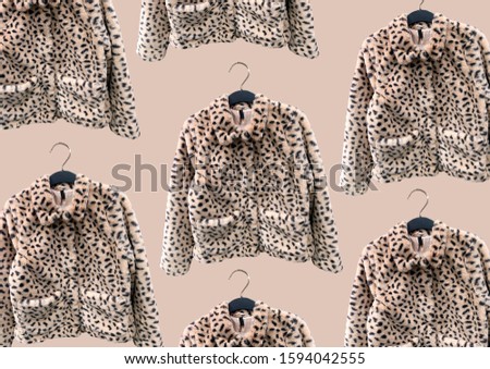 Faux leopard coats with pockets on hanger isolated on brown background. Composition of clothes. Flat lay, top view, copy space. Ladies' Trench Coat. Winter clothes pattern. Strict classic white coat