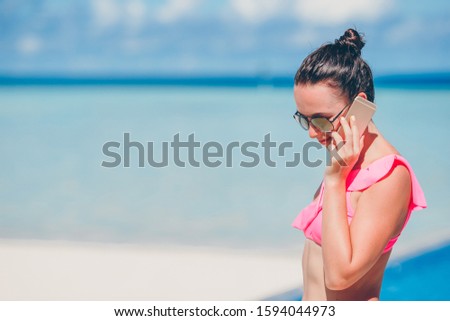 Young woman talks by smartphone on beach vacation