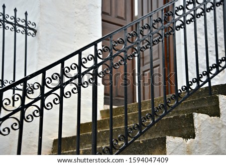 Traditional Greek Orthodox church handcrafted iron stairway railing with a wooden entrance door on the background in Leonidio Arcadia, Peloponnese Greece. 