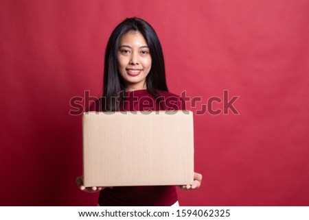 Delivery, relocation and unpacking.  young asian woman holding cardboard box on red background.