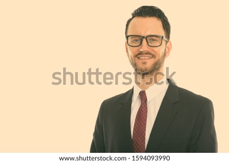 Studio shot of young happy businessman smiling while wearing eyeglasses