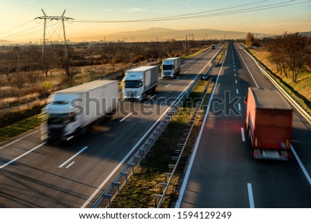 Fast blurred delivery trucks in high speed motion driving on a highway