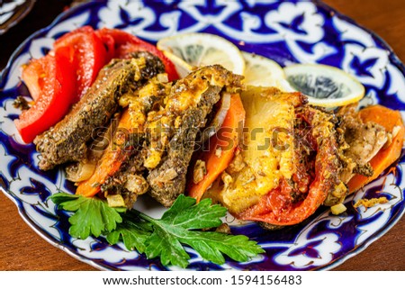 Traditional oriental cuisine. Dish for the holiday of Navruz from meat, fish, pineapple, paprika, tomato and lemon. Serving dishes in Uzbek plates. Copy space, background image