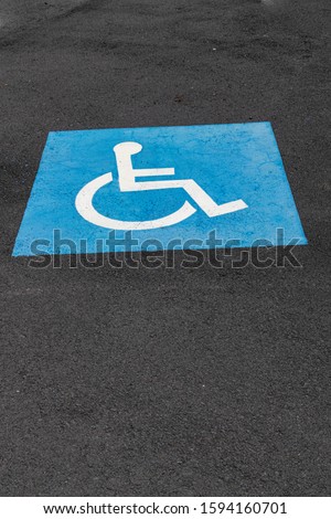 disabled parking blue/white sign, painted on asphalt surface
