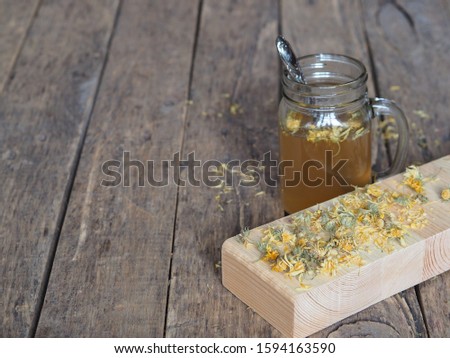 Dried flowers
 calendula and brewed medicinal tea on a wooden ancient table.