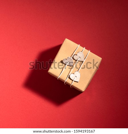 New Year and Christmas composition. Gift box on red paper background with shadow. Top view, flat lay, copy space