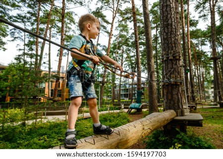 Go Ape Adventure. Climber child on training. Child climbing on high rope park. Roping park. boy with safety carbine goes on a rope in adventure climbing high wire park Royalty-Free Stock Photo #1594197703
