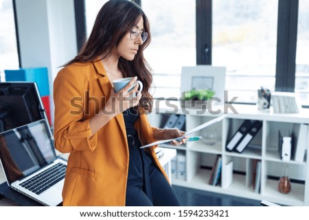 Shot of business young woman drinking coffee while working in the office.
