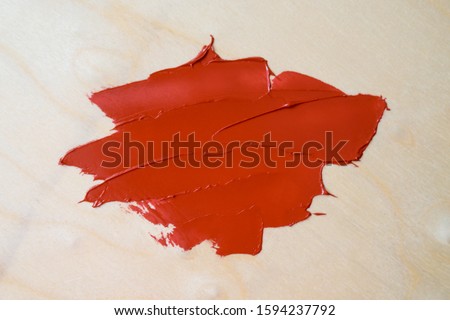A smear of red oil paint on a wooden background. Layout for your design.