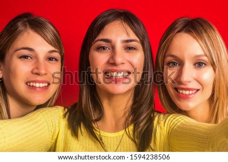 Stock photo of three girls together facing the front on a red background