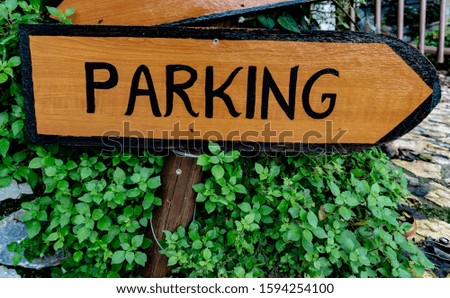 Painted sign Parking on wooden arrow against green grass.