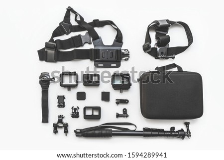 Flat lay of action camera with accessories on white background top view.