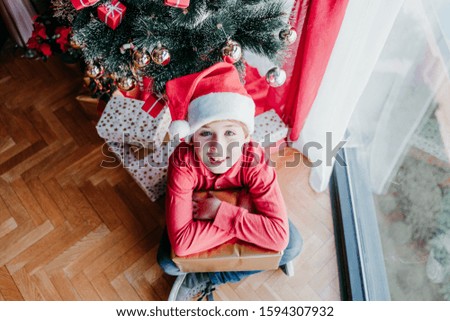 portrait of beautiful boy at home sitting by the christmas tree and presents