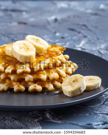 three waffles with honey on the dark plate