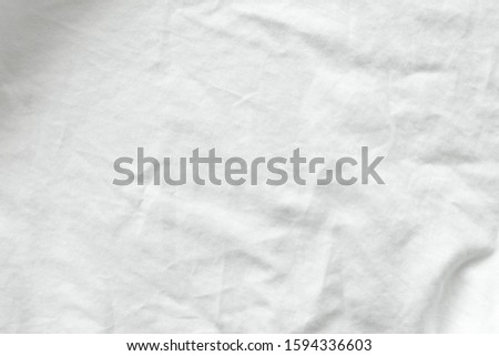 Close up shot of wrinkled white cotton shirt texture. Can see detail of the natural soft fabric. Crease Clothing textile or untidy bed sheet cover. Background wallpaper with copy space for edit