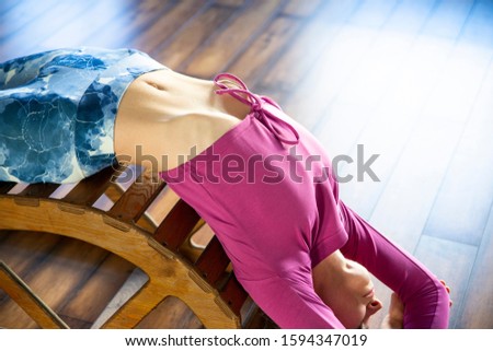 Young woman in yoga pose on wooden bench