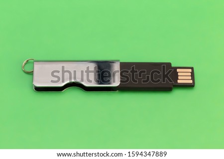 Rectangular metallic USB flash drive on a green background. Close-up