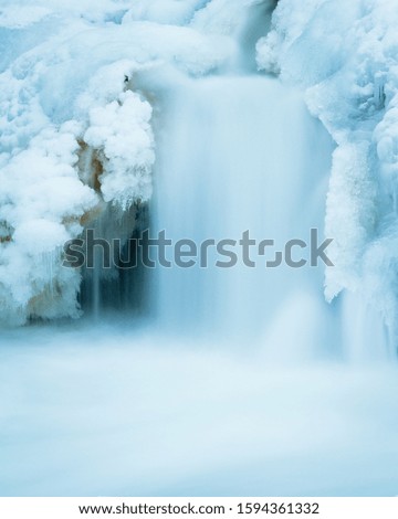 Canadian waterfall in winter flowing over snow and ice. Water in cold season. Canada.