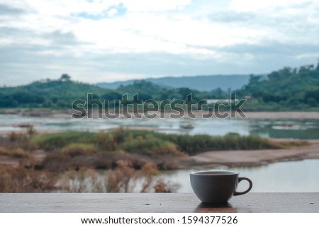 white coffee cup on wooden table Mekong river background vintage style effect picture