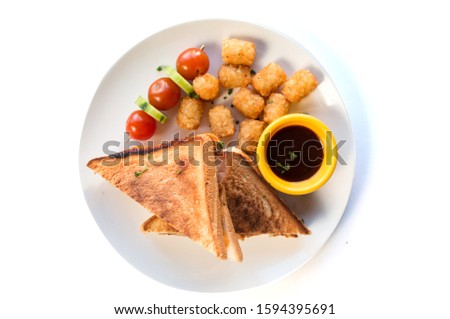 Top view image of two slices of toast bread with hash browns, tomatoes