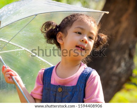 A little girl was happily standing in an umbrella against the rain, Be a part of learning outside of the school in the nature park