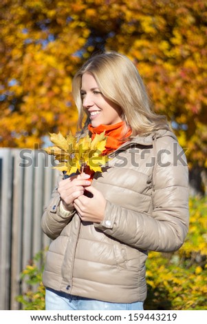portrait of young beautiful woman with bouquet of maple leaves
